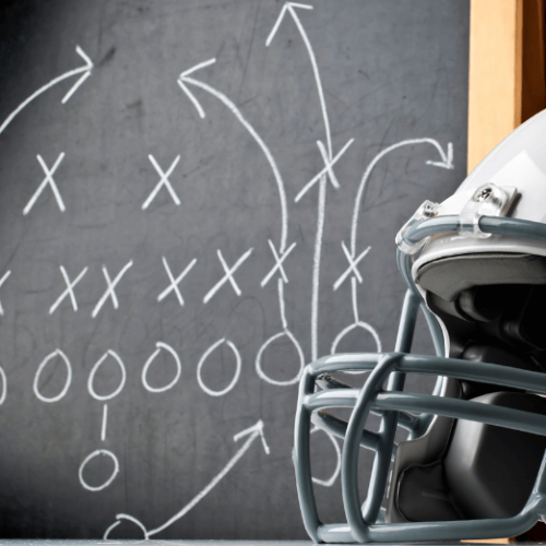 Photo of a football helmet sitting in front of a chalk board with a football play drawn on it.
