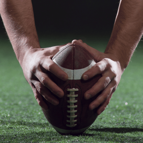 Stylized photo of a player holding a football and preparing to snap it to the quarterback.