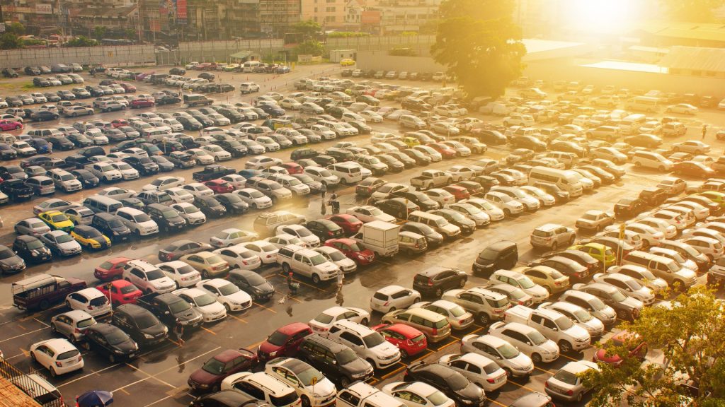 Overhead view of a parking lot with several cars of various size and color.