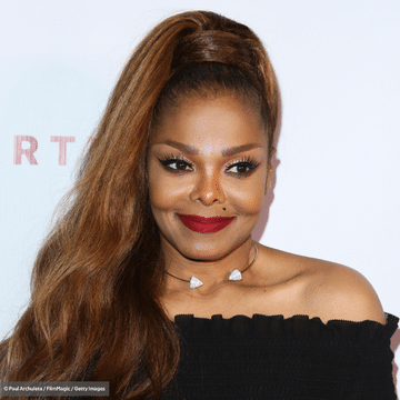 Picture of Janet Jackson in a black dress and red lipstick smiling