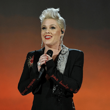 Pink wearing a black blazer and holding a micro