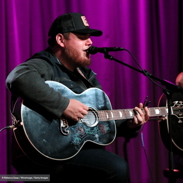 Photo of Like Combs playing a blue guitar and singing into a microphone.