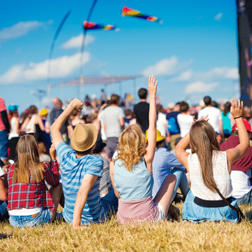Five people sitting on the grass at outdoor festival