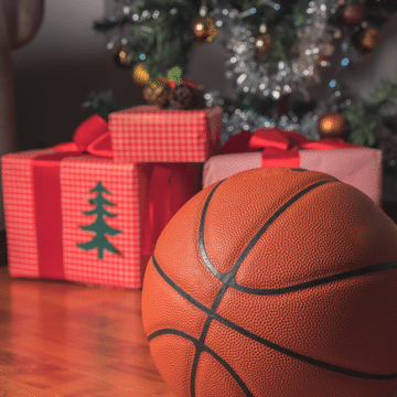 Photo of a basketball in front of a Christmas tree and presents.