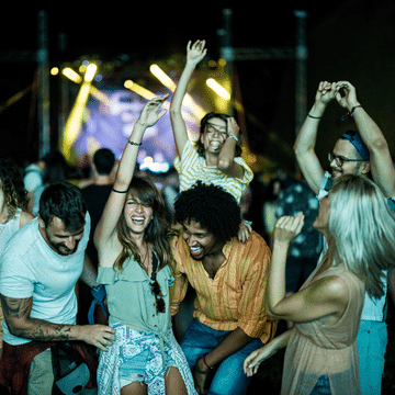 Photo of a group of people dancing with stage lights behind them.