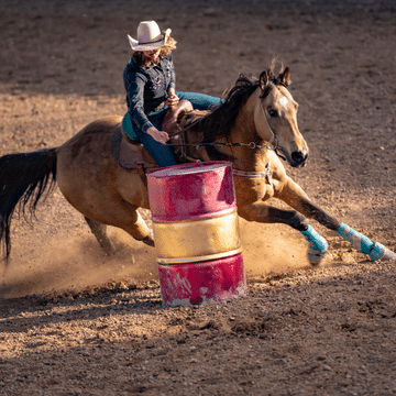 Woman riding a horse around a barrel