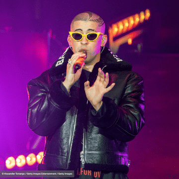Photo of artist Bad Bunny holding a microphone and performing on stage.