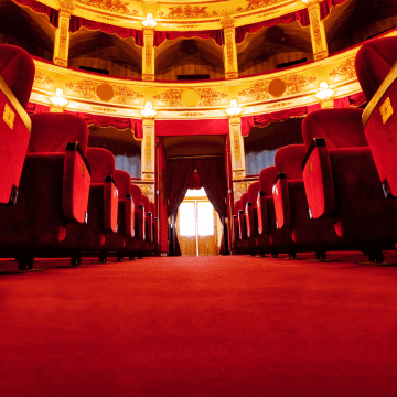 An empty red theatre shows an aisle surrounded by chairs.