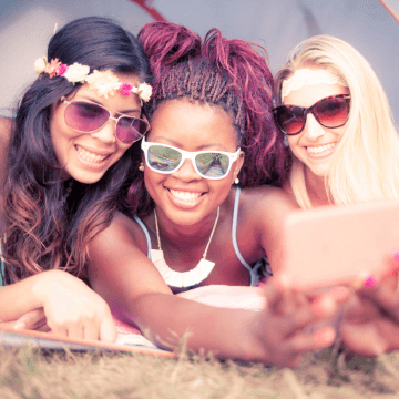 Three young women smile and pose for a selfie together.