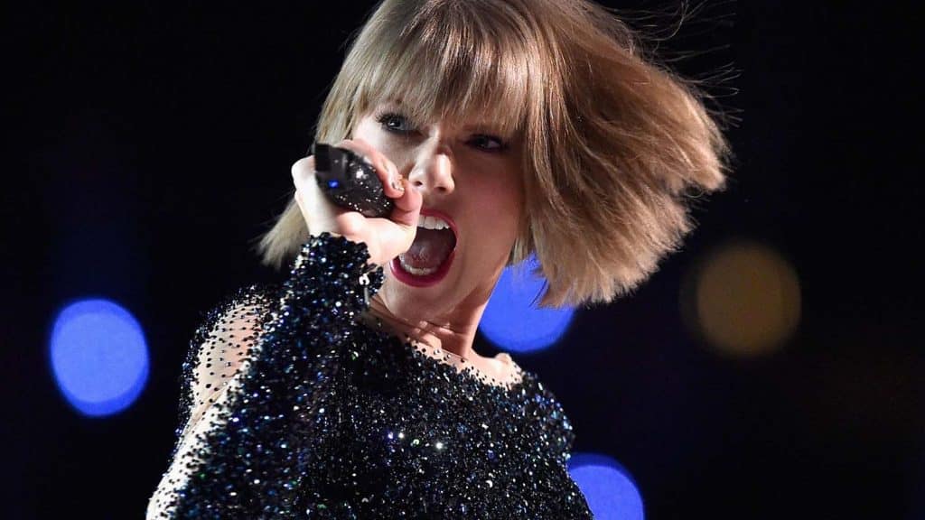 Taylor Swift singing powerfully into a microphone during a preformance.