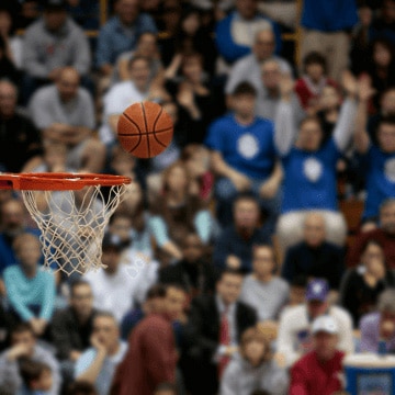 A ball falls toward the hoop with a large crowd in the background.