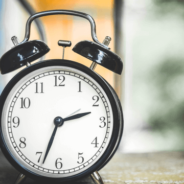 A black clock on a wooden table.