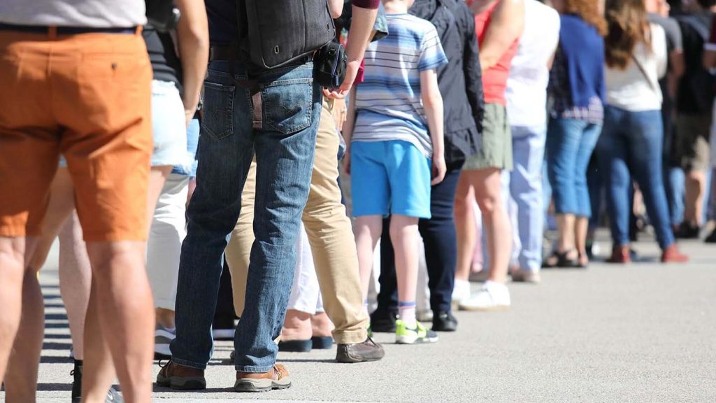 A long line of people wait to get tickets outside of a venue.