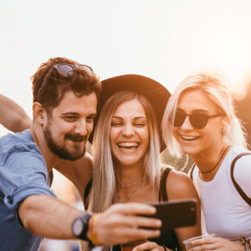 A man and two women smile for a selfie.