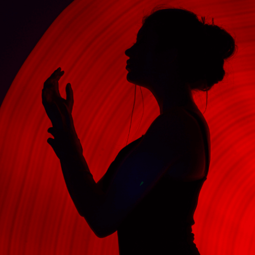 Photo of a woman's silhouette in front of a red screen.