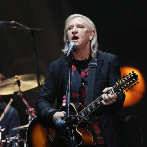 Image of Joe Walsh singing and playing the guitar on stage