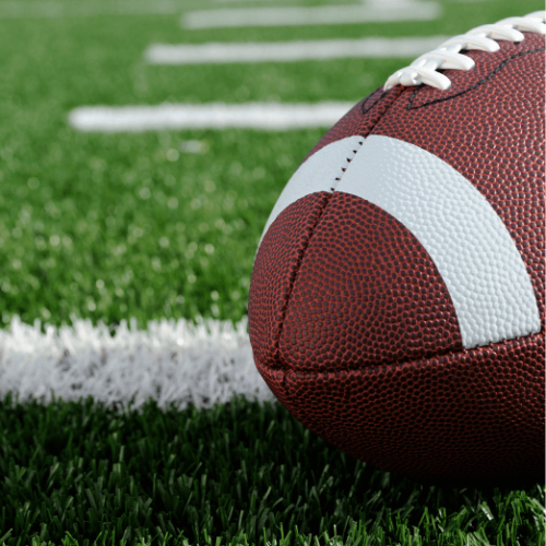 Photo of a football on a green grass football field.