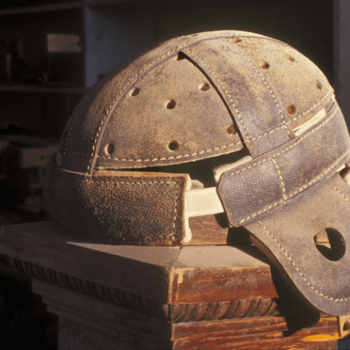 Photo of vintage leather football helmet on top of a stack of books.