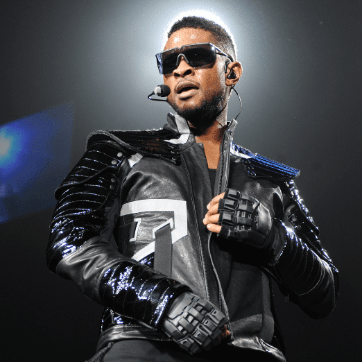 Photo of Usher performing in black sunglasses and a black leather jacket.