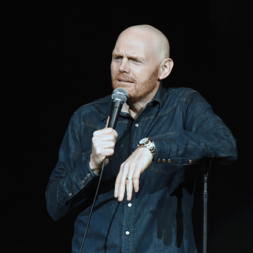Photo of Bill Burr holding a microphone during a stand-up show.
