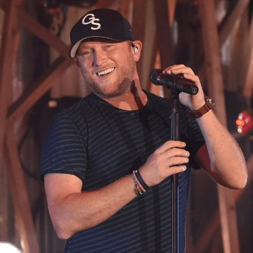 Image of Cole Swindell smiling while performing and holding a microphone