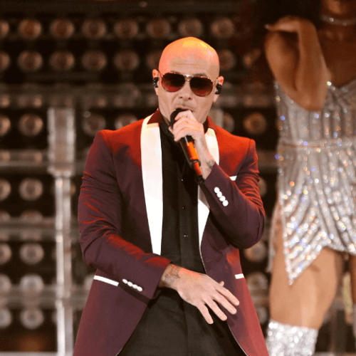 Image of Pitbull performing on stage wearing dark shades and a dark red blazer